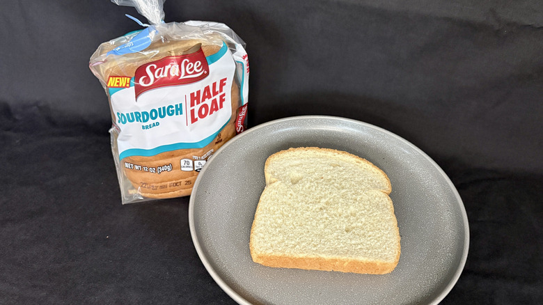 Bagged loaf of Sara Lee Sourdough next to slice of bread on gray plate