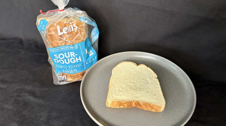Bagged loaf of Lewis Bake Shop  Sourdough next to slice of bread on gray plate
