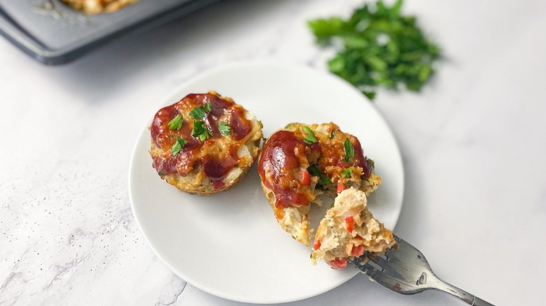 a fork with a piece of glazed chicken meatloaf muffins on a plate