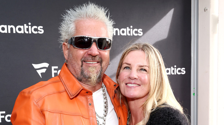 Guy Fieri in an orange jacket and Lori Fieri in a black jacket