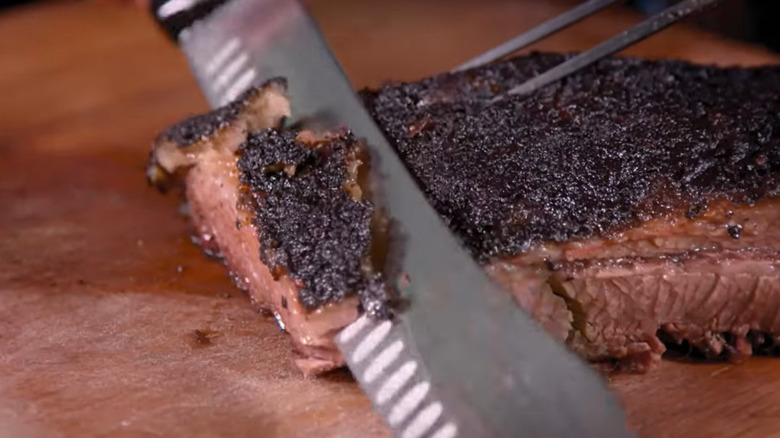 A chef's knife slicing smoked brisket at Cochon Volant BBQ restaurant
