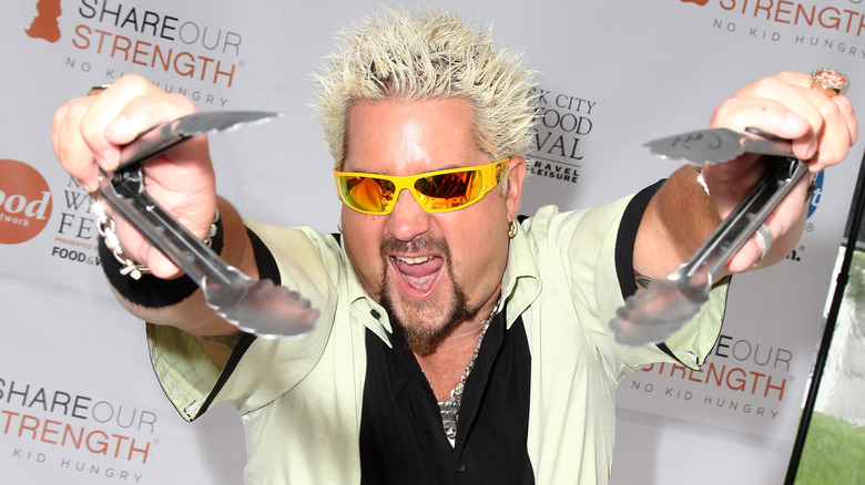 Guy Fieri in sunglasses, holding tongs