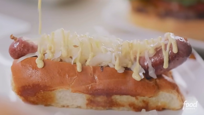 Hot dog in bun with kraut and mustard drizzle