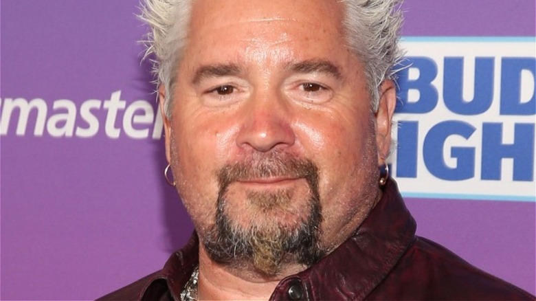 Guy Fieri smiles in dark red shirt