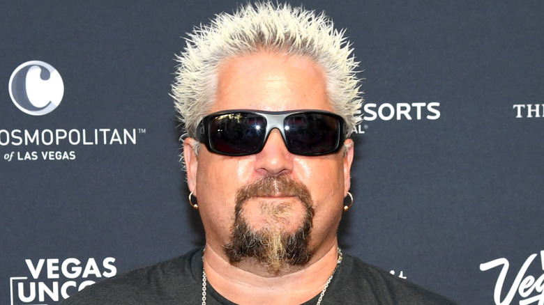 Guy Fieri in sunglasses posing for cameras at publicity event