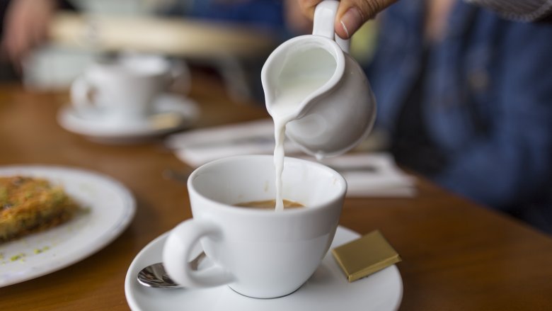 pouring cream into coffee