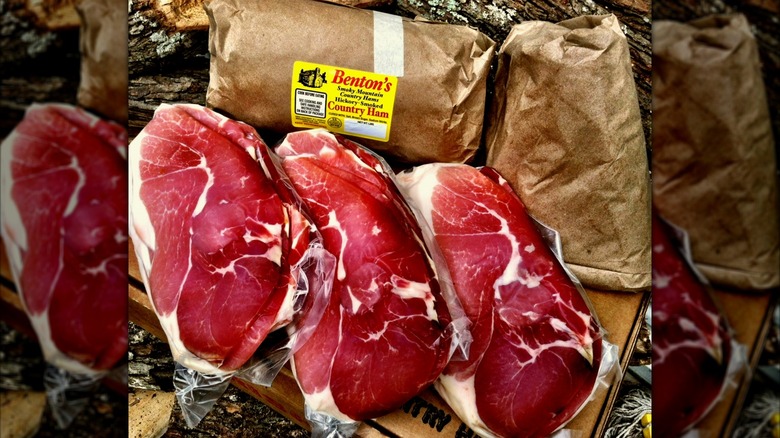 Three whole hickory smoked country hams next to hams wrapped in brown paper