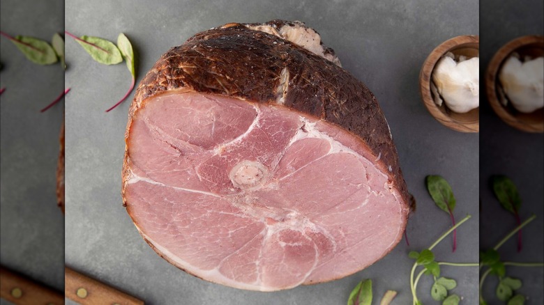Half of a bone-in ham on a slate cutting board