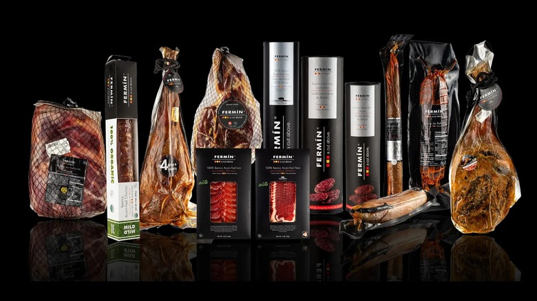 Range of Fermin's Iberico ham products in packaging, including whole ham legs, sliced hams, and chorizo