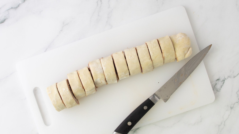 Sliced puff pastry log on cutting board next to knife