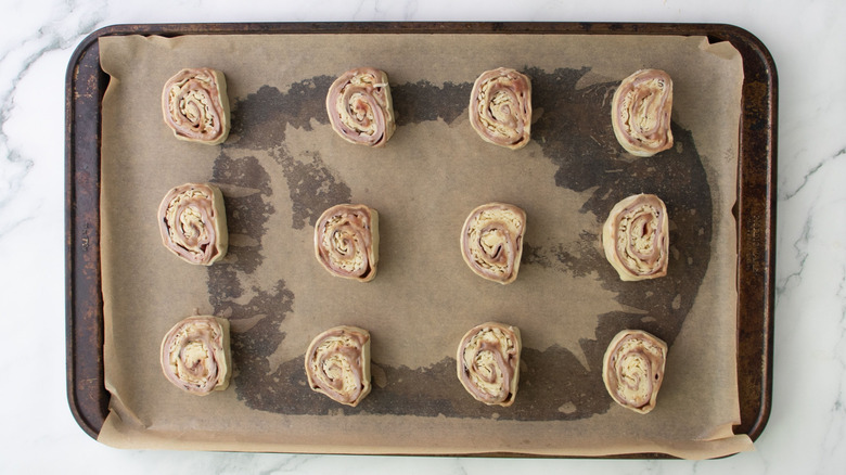 Unbaked pinwheels arranged on lined baking sheet