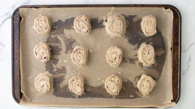 Unbaked pinwheels on baking sheet brushed with egg wash