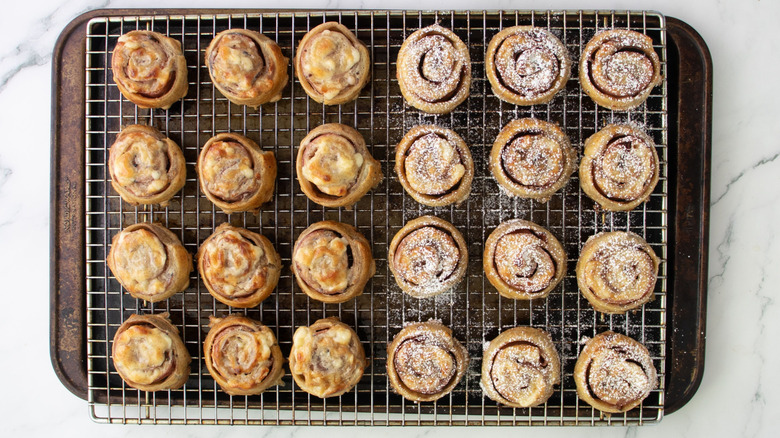 Pinwheels on wire rack with half dusted in powdered sugar