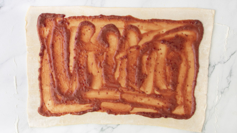 Puff pastry sheet with mustard-jam mixture spread over it