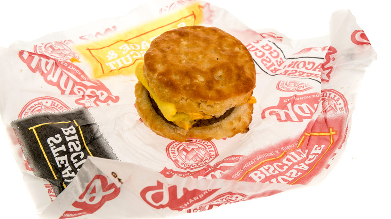 A biscuit sandwich stuffed with eggs and sausage sitting on top of a Hardee's sandwich wrapper.