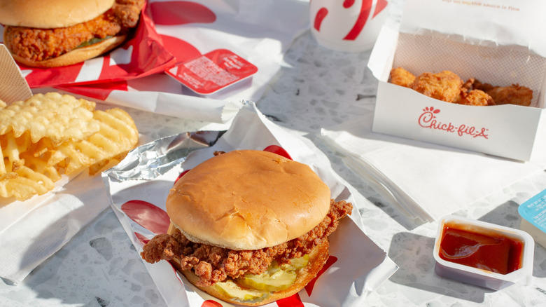 Chick-fil-A chicken sandwiches, chicken strips, fries, and opened sauce packets on a table