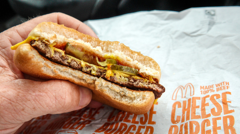 A hand holding a cross-section of a McDonald's cheeseburger