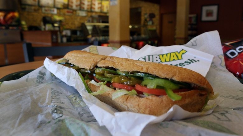 Close-up of an unwrapped Subway sandwich inside a Subway store