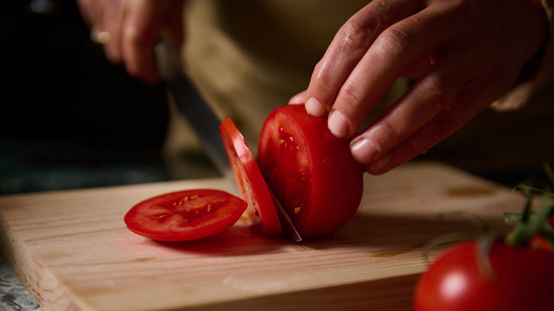 Slicing tomato on a wooden cutting board