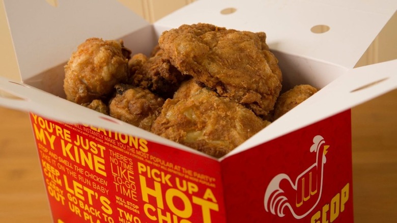 Minit Stop fried chicken in red, white, and yellow paper box on wooden table with white background