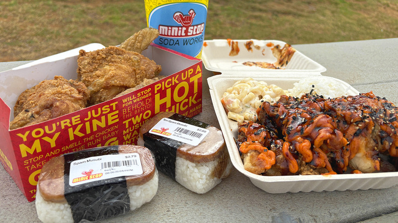 Fried chicken, Spam musubi, plate lunch, and drink from Minit Stop on picnic table.