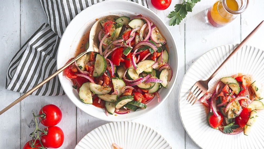 cucumber tomato salad in white bowls with striped cloths