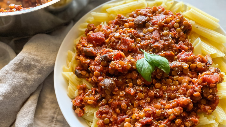 plate of lentil bolognese on penne with fresh basil on top