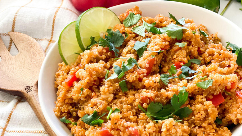 Quinoa Spanish rice in white bowl with cilantro and lime slices