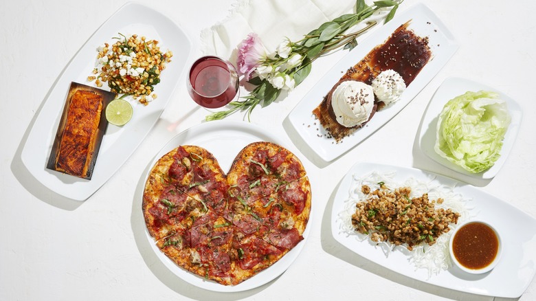 heart-shaped pizza with side dishes and salad