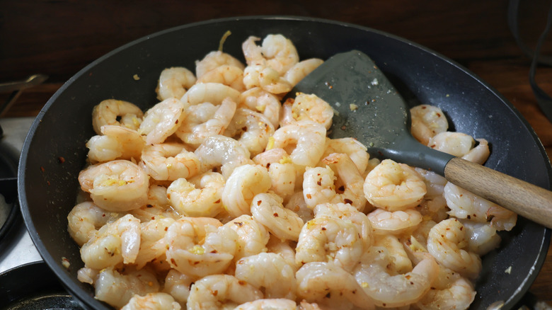 skillet full of cooked shrimp with a spatula in it