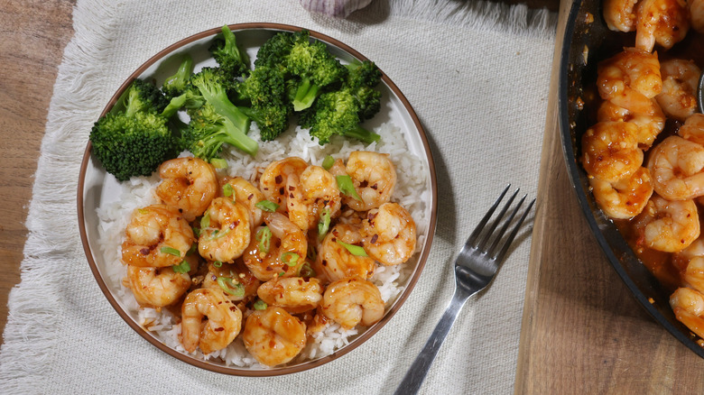 plate of spicy honey garlic shrimp over rice with steamed broccoli