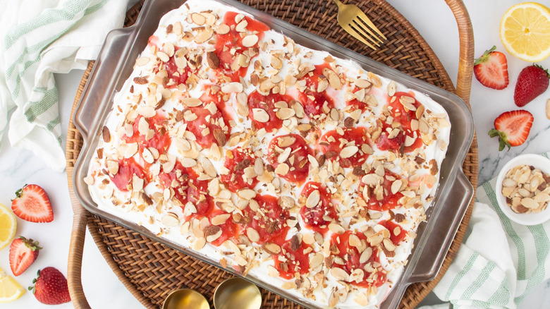 Heaven on earth cake in baking dish topped with strawberries and sliced almonds