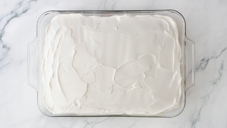 Whipped cream layer on top of cake in baking dish