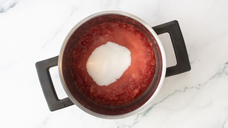 Mashed strawberries and sugar in pot