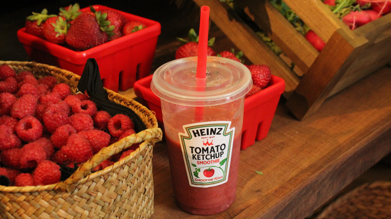 Heinz ketchup smoothie in a cup, next to baskets of raspberries and strawberries