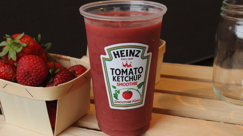 Tomato smoothie next to a wooden basket of strawberries