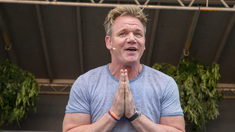 Gordon Ramsay in a light T-shirt making prayer hands