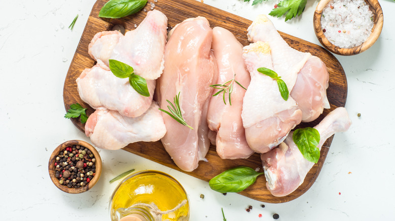 raw chicken on wooden cutting board with seasonings