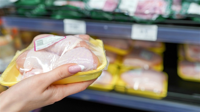 Woman holding packaged chicken in grocery store