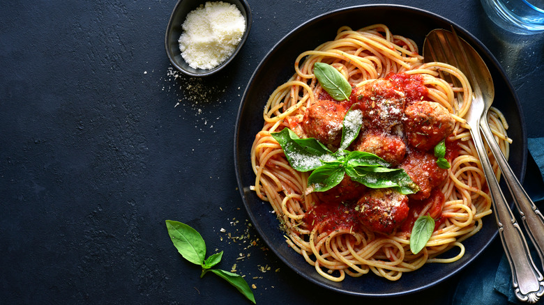 bowl of spaghetti and meatballs with basil and parmesan cheese