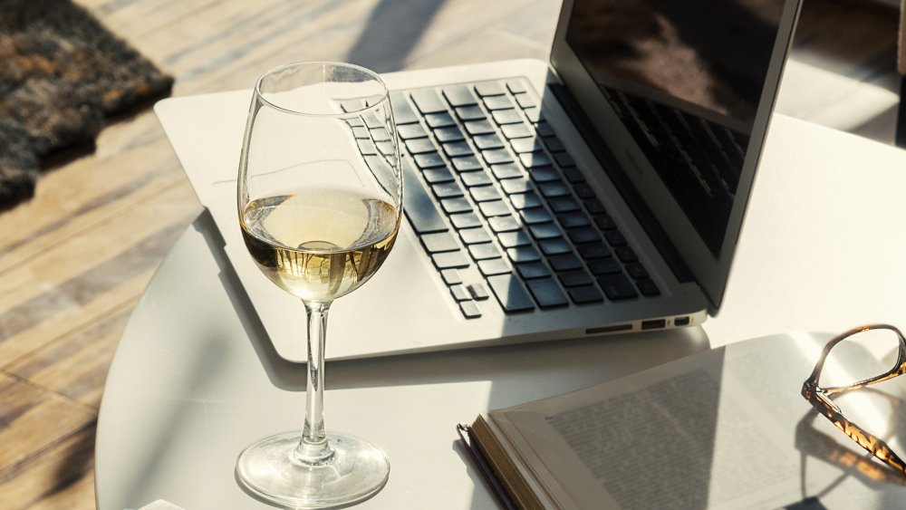 glass of white wine with open laptop on a side table