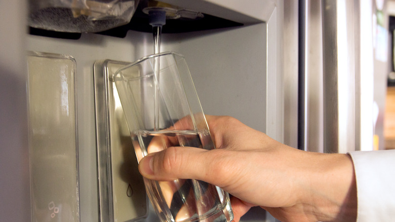 Person getting water from fridge water dispenser