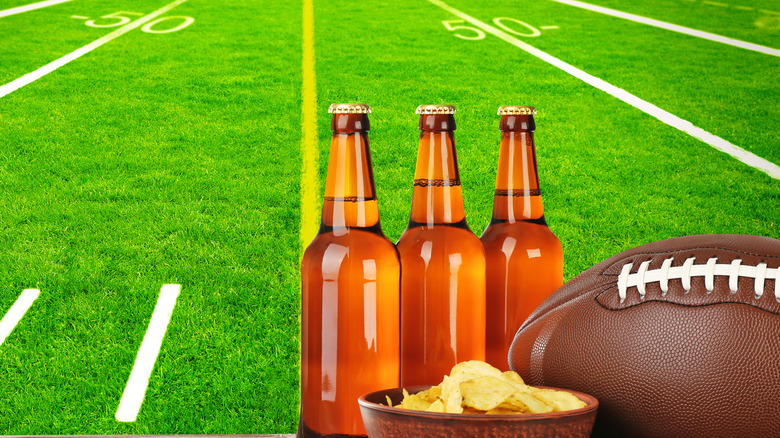 bottles of beer and a bowl of potato chips next to football