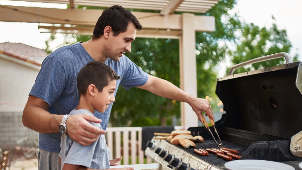 dad and son cooking on gas grill