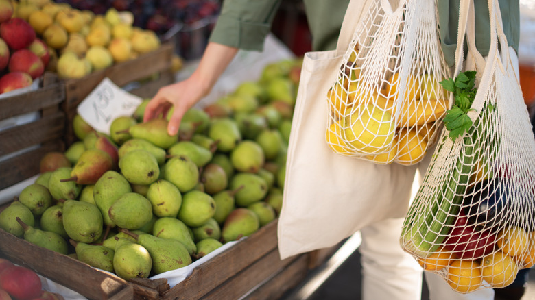 Person selecting pear from produce crate