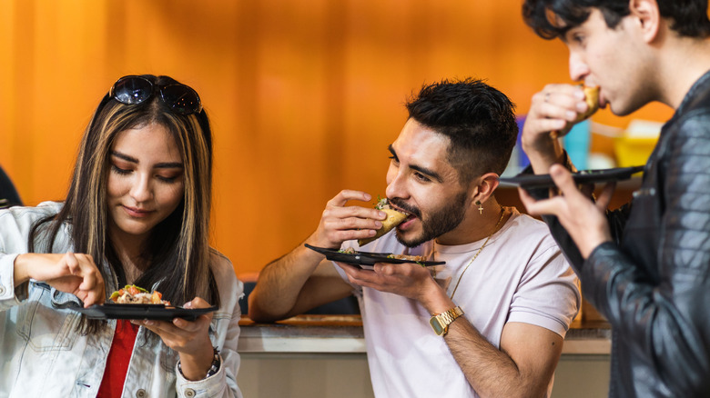 People eating tacos on black plates