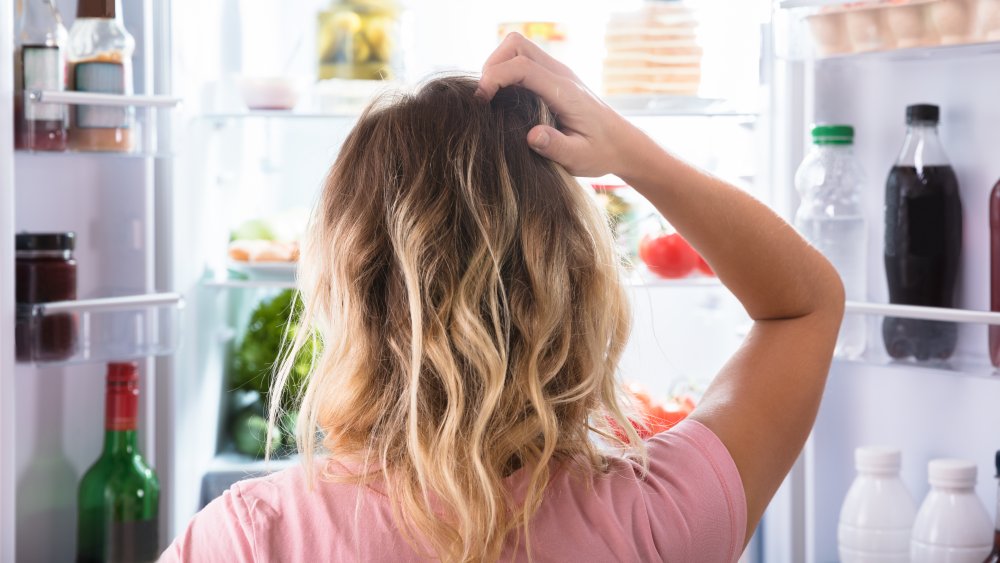 woman looking confused in front of refrigerator