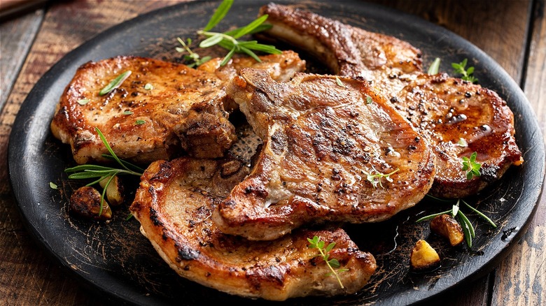 A large plate of cooked pork chops sprinkled with herbs