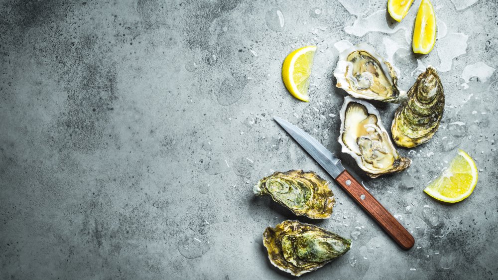 oysters on ice next to lemon wedges and an oyster knife