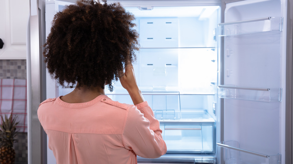 Woman looking into empty fridge